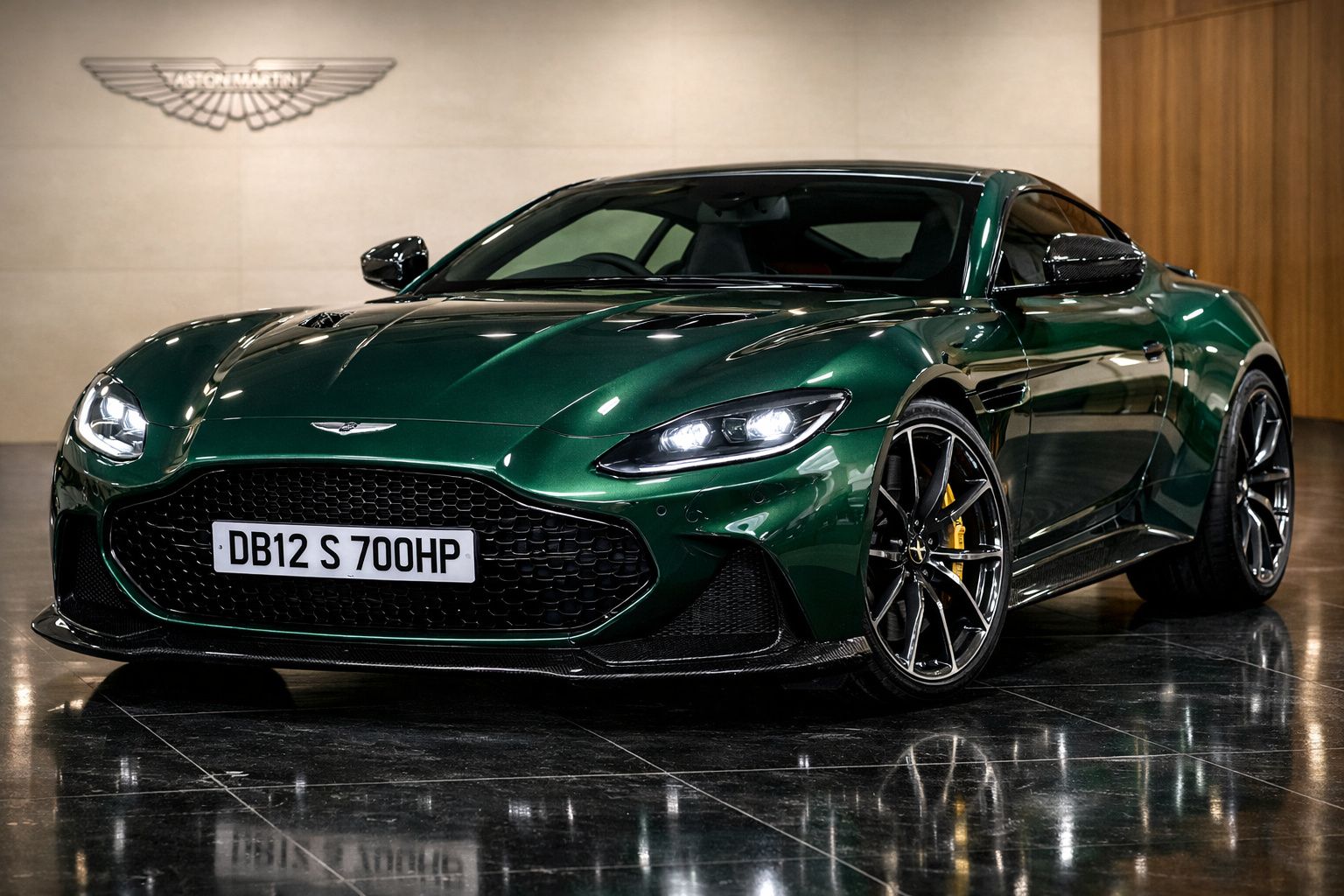 Carro desportivo Aston Martin DB12 verde metálico estacionado em espaço interior com piso refletor.