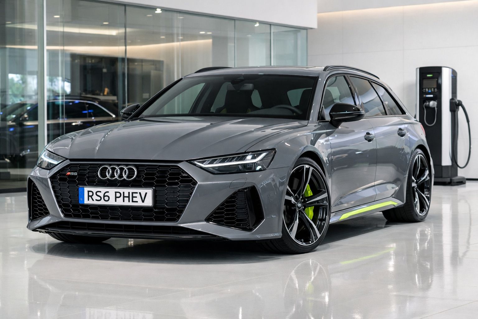 Carro Audi RS6 PHEV cinzento estacionado em showroom moderno com carregador elétrico ao fundo.