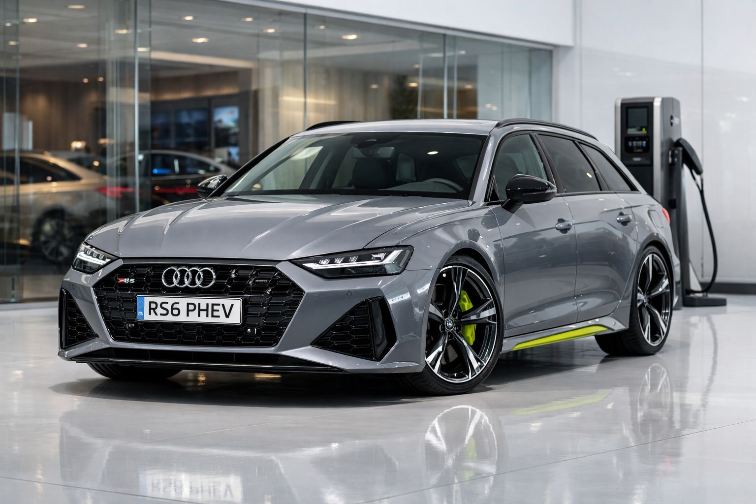 Automóvel Audi RS6 PHEV cinzento estacionado junto a um carregador elétrico numa área interior moderna.