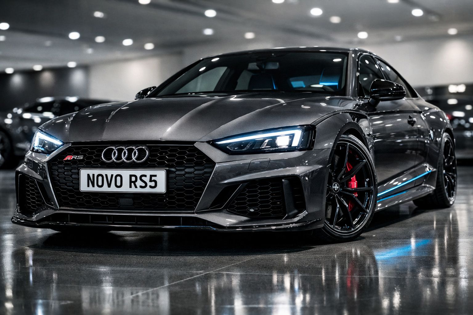 Carro desportivo Audi RS5 cinza escuro estacionado em piso brilhante, com faróis acesos.