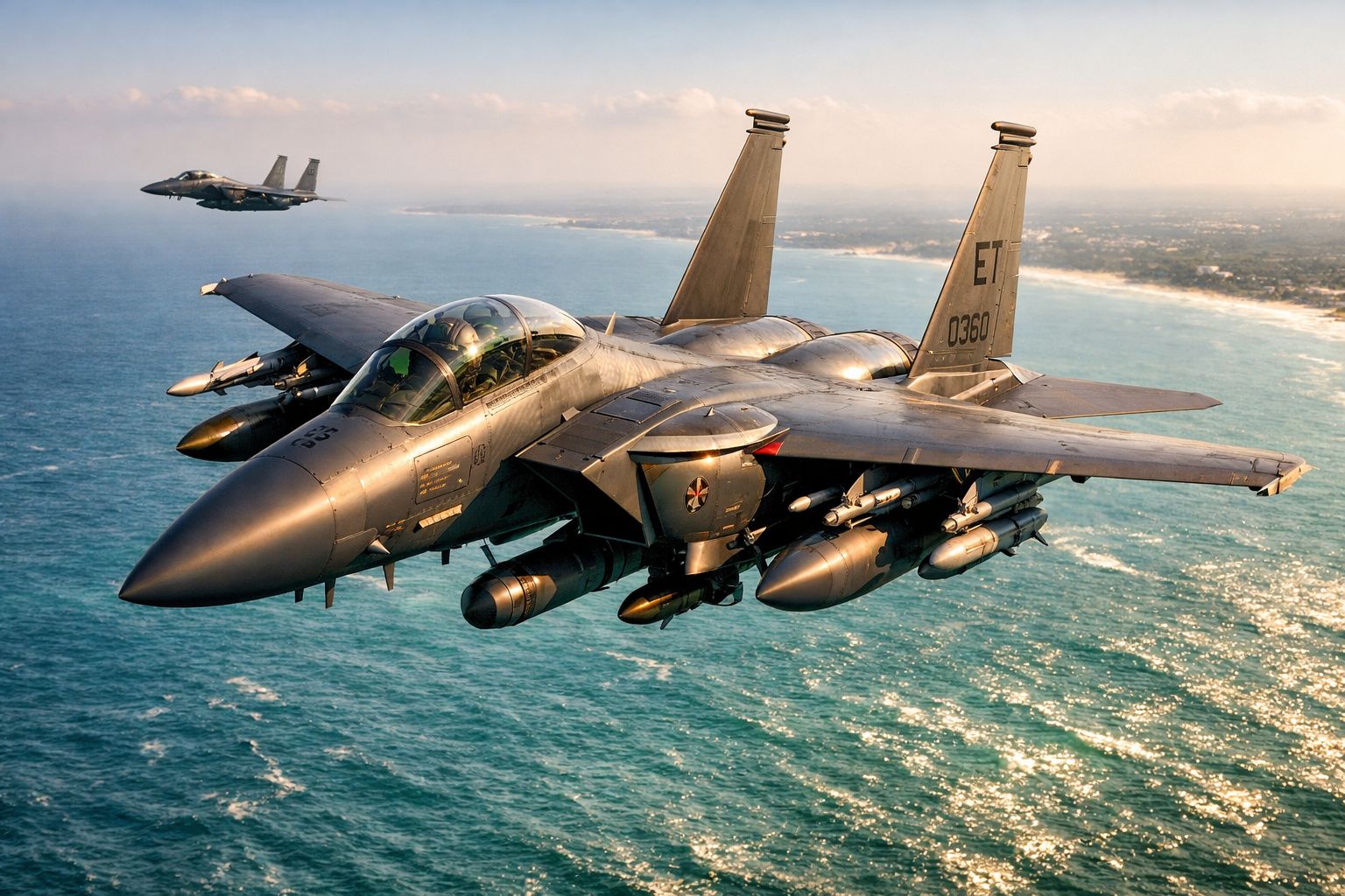 Dois caças militares voando sobre o oceano próximo à costa ao pôr do sol.